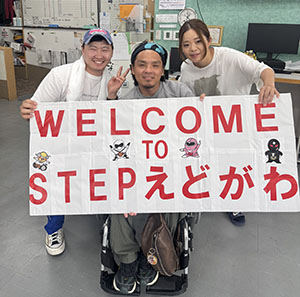 ステップえどがわで歓迎を受けるニャムカさんとサンチョさん。スタッフと一緒にウェルカムボードを持って。